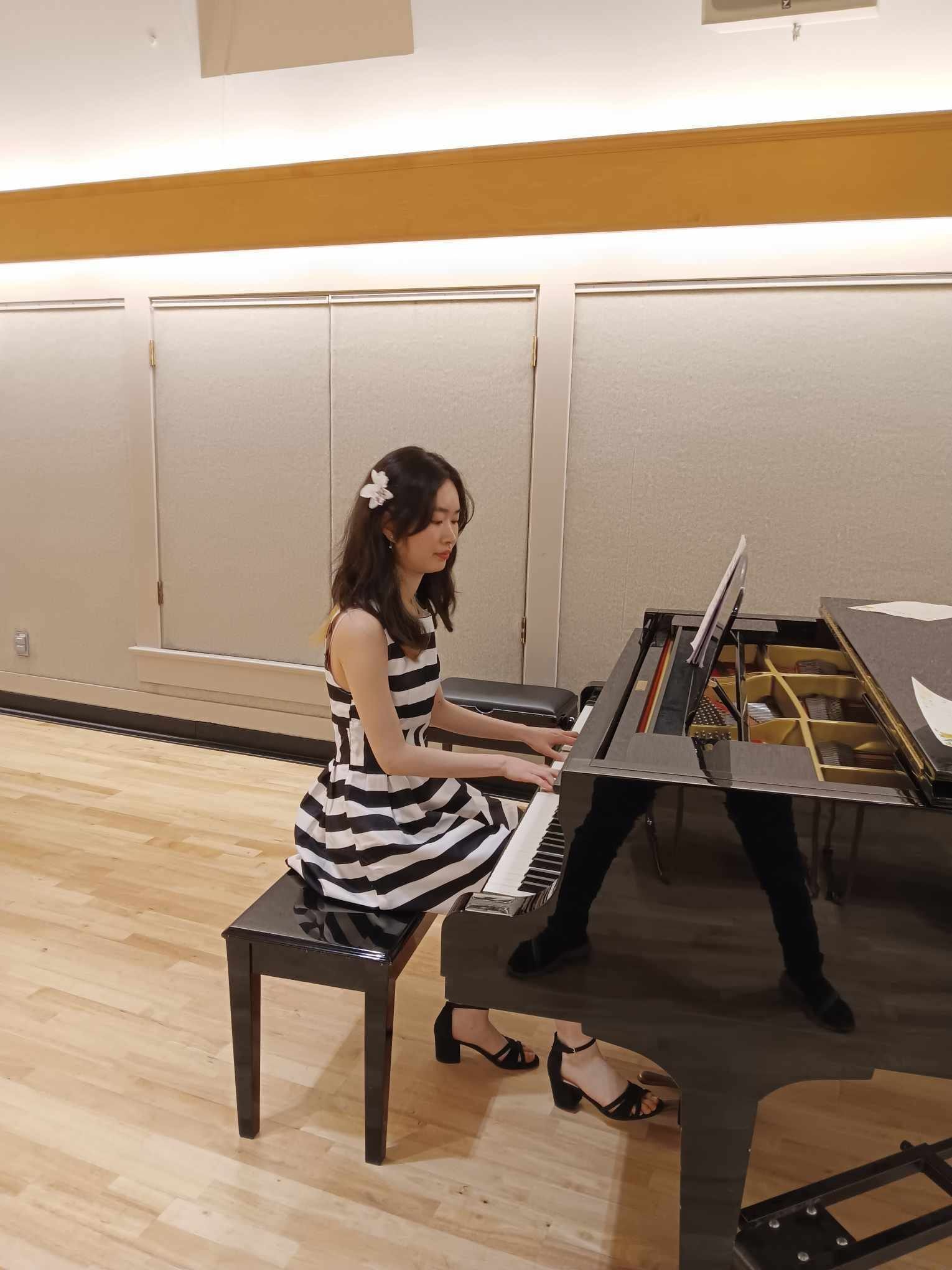 Cher playing a black grand piano at a community concert